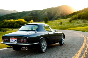 photo of old classic MG car on a mountain road sun setting behind it