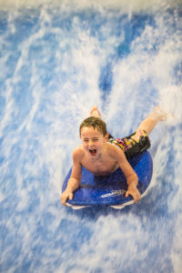 image of boy on a boogie board going down a wave with a big smile