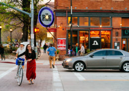 Moss Image, Marketing, Chris Moss, picture of a girl in red dress walking bicycle across a street with restaurant behind
