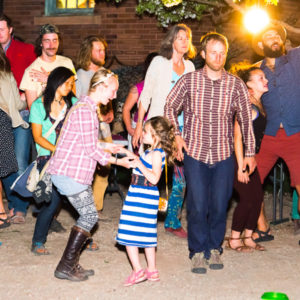 girl in blue striped dress dancing at a party with people all around