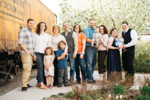 Group Family photo with people smiling next to a train car with trees in the background