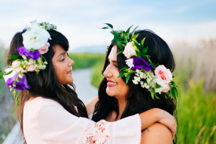 Portrait, Moss iMage, Moab Photographer, Mother and daughter smiling at each other with purple and pink flowers in their hair and blue sky in the background