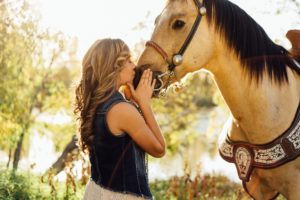 Portrait, Moss Image, Girl in a blue jean shirt kissing her horse on the nose