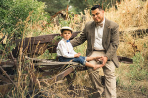 Location Photography, picture of a father and son in fifties style clothing sitting on old machinery looking at the camera
