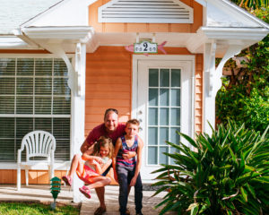 Beach front cabin, man with two children in front of cabin